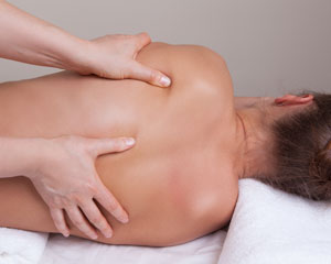 En person som ligger på sidan och får en djup muskelterapi massage.