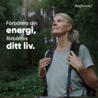 Bilden visar en leende kvinna som går en promenad i skogen