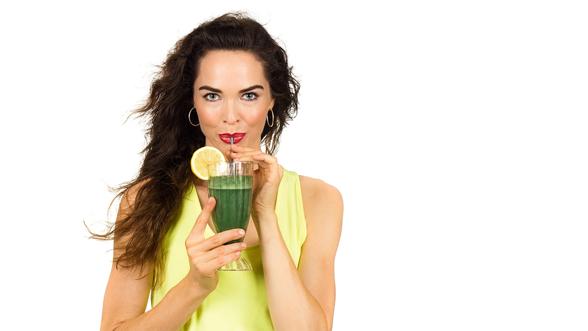 En kvinna dricker spirulina med sugrör – är spirulina för viktminskning en verklighet eller en myt?