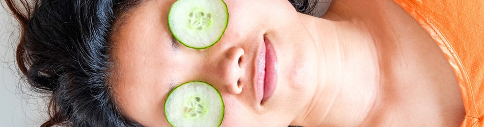 En person som ligger med gurkor över ögonen för att få bort påsar under ögonen