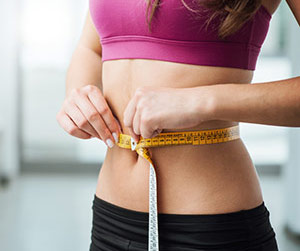 En kvinna som mäter sitt midjemått efter att ha gjort sitt pass med vibrationsträning